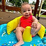 baby, infant, smiling, sitting, inflatable_pool, water, red_swimsuit, playful, deck, outdoor, summer, foot, yellow_inflatable, child, happy, cute, sunny, blue, toy, toddler