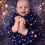 Orion is registered to the contest to win money with this photo: baby, background_bokeh, blue_clothing, child, close_up, cute, expression, face, feet, hands, happy, indoor, infant, pajamas, playful, portrait, skin, smiling, soft_lighting, stars