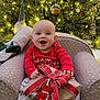 armchair, baby, celebration, child, christmas, christmas_tree, cozy, decorations, festive, gift, happy, holiday, indoor, lights, ornaments, present, red_clothing, seasonal, smiling, wrapped_gift