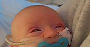 Maddox is registered to the contest to win money with this photo: baby, pacifier, nasal_cannula, hospital, medical_equipment, swaddled, infant, face, person, sleepy, newborn, closeup, healthcare, bed, soft_fabric, cuddle, young_child, indoor, medical_care, patient