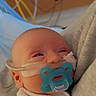 baby, pacifier, nasal_cannula, hospital, medical_equipment, swaddled, infant, face, person, sleepy, newborn, closeup, healthcare, bed, soft_fabric, cuddle, young_child, indoor, medical_care, patient