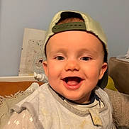 Ozan participe au concours pour gagner de l'argent avec cette photo : baby, blanket, cap, child, clothing, cute, expression, face, happy, headwear, indoor, infant, joyful, mouth_open, person, portrait, sitting, smiling, star_pattern, young