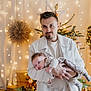 Noah a rejoint le concours — aidez-le/la à gagner de superbes lots ! baby, man, child, christmas_tree, holiday, lights, decorations, gift_boxes, indoors, family, warm_lighting, smiling, portrait, festive, clothing, holding, beard, white_jacket, cozy, celebration