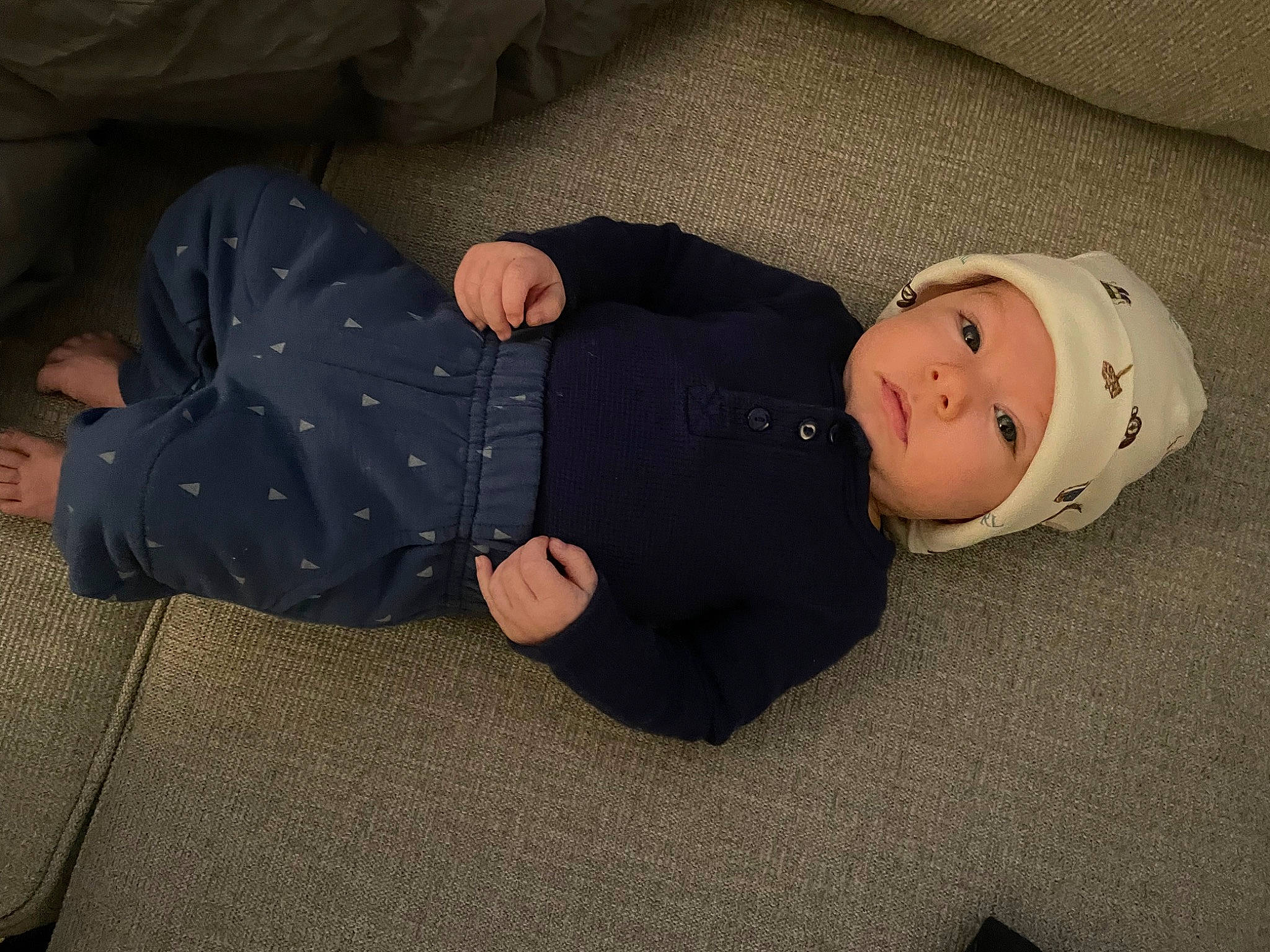 Mark is registered to the contest to win money with this photo: baby, baby_products, baby_toddler_clothing, carmine, child, comfort, flooring, fun, hardwood, headwear, human_body, leg, linens, person, room, sitting, sleeve, smile, sock, toddler