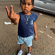 Demetrius joined the competition — help win amazing prizes! child, boy, braided_hair, peace_sign, blue_shirt, shorts, sneakers, outdoor, urban, pavement, car, parking_lot, serious_expression, standing, jewelry, necklace, bracelet, daylight, casual_clothing, litter