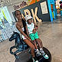 Demetrius is registered to the contest to win money with this photo: child, woman, indoor, statue, horse, smile, bucket_hat, shorts, sneakers, tattoo, playful, decor, letters, joyful, pose, floor, backpack, light, person, happy