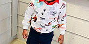 Demetrius is registered to the contest to win money with this photo: toddler, child, smiling, braided_hair, sweatshirt, dinosaurs, shorts, sneakers, socks, indoor, wall, corner, floor, happy, person, standing, portrait, casual_clothing, cute, playful