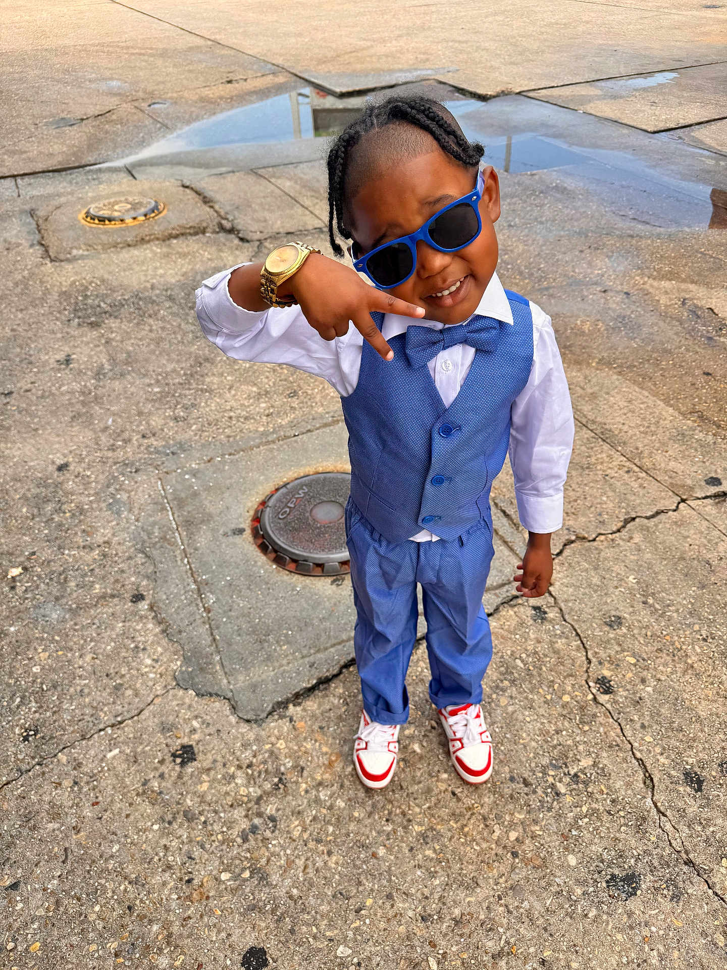 Demetrius is registered to the contest to win money with this photo: child, boy, blue_suit, bowtie, sunglasses, watch, peace_sign, street, concrete, puddle, outdoor, fashion, smiling, shoes, hair, standing, casual, cool, confident, portrait