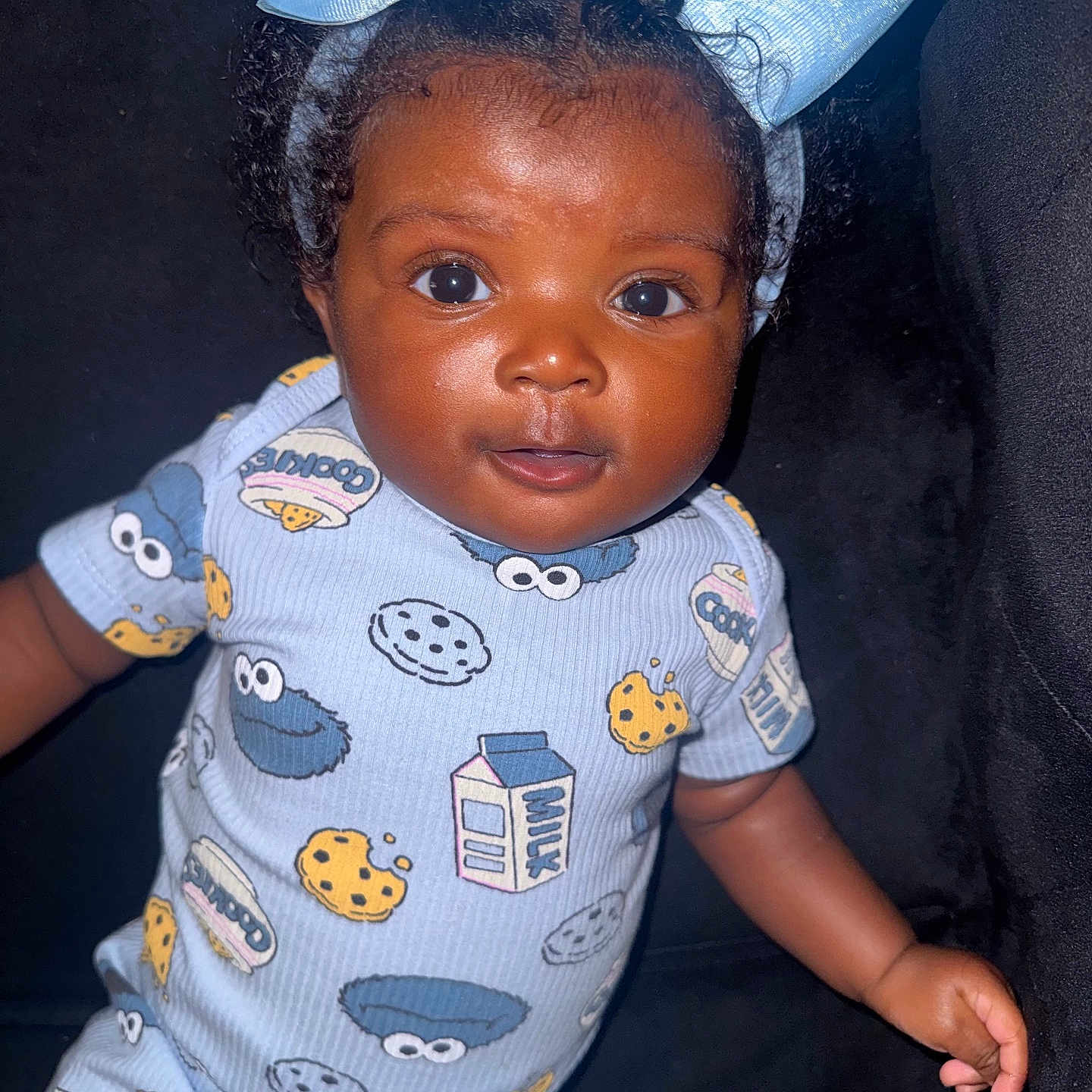 Daige Dior joined the competition — help win amazing prizes! baby, blue_bow, child, closeup, clothing, cookie, cookie_monster, curly_hair, cute, dark_background, face, happy, headband, indoors, infant, milk_carton, onesie, person, portrait, smile