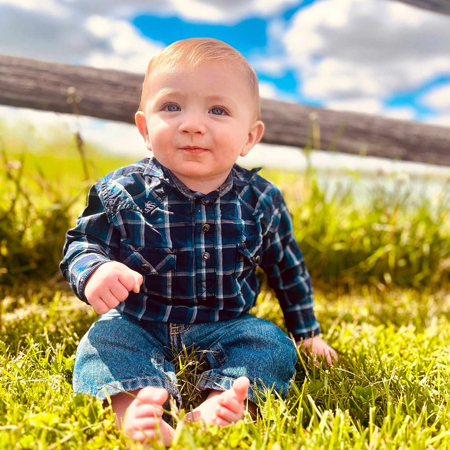 Elliot joined the competition — help win amazing prizes! baby, barefoot, blue_sky, casual_clothing, child, clouds, cute, daylight, grass, greenery, jeans, nature, outdoor, person, plaid_shirt, portrait, sitting, smiling, sunlight, wooden_fence