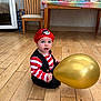 Teddy is registered to the contest to win money with this photo: toddler, child, pirate_costume, red_cap, striped_shirt, golden_balloon, wooden_floor, chair, table, colorful_cloth, indoor, baby, costume, party, flooring, seat, furniture, face, person, celebration