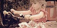 Rose a rejoint le concours — aidez-le/la à gagner de superbes lots ! child, tricycle, outdoor, pink, flowered_skirt, short_sleeve_shirt, garden, leaves, bike, handlebars, footwear, young_child, curly_hair, play, summer_clothing, concrete_ground, toy, person, nature, daytime