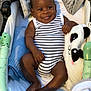 baby, infant, smiling, striped_onesie, panda_plushie, blanket, stroller, cozy, happy, cute, child, soft_toy, comfort, indoors, portrait, relaxed, skin, feet, hand, face