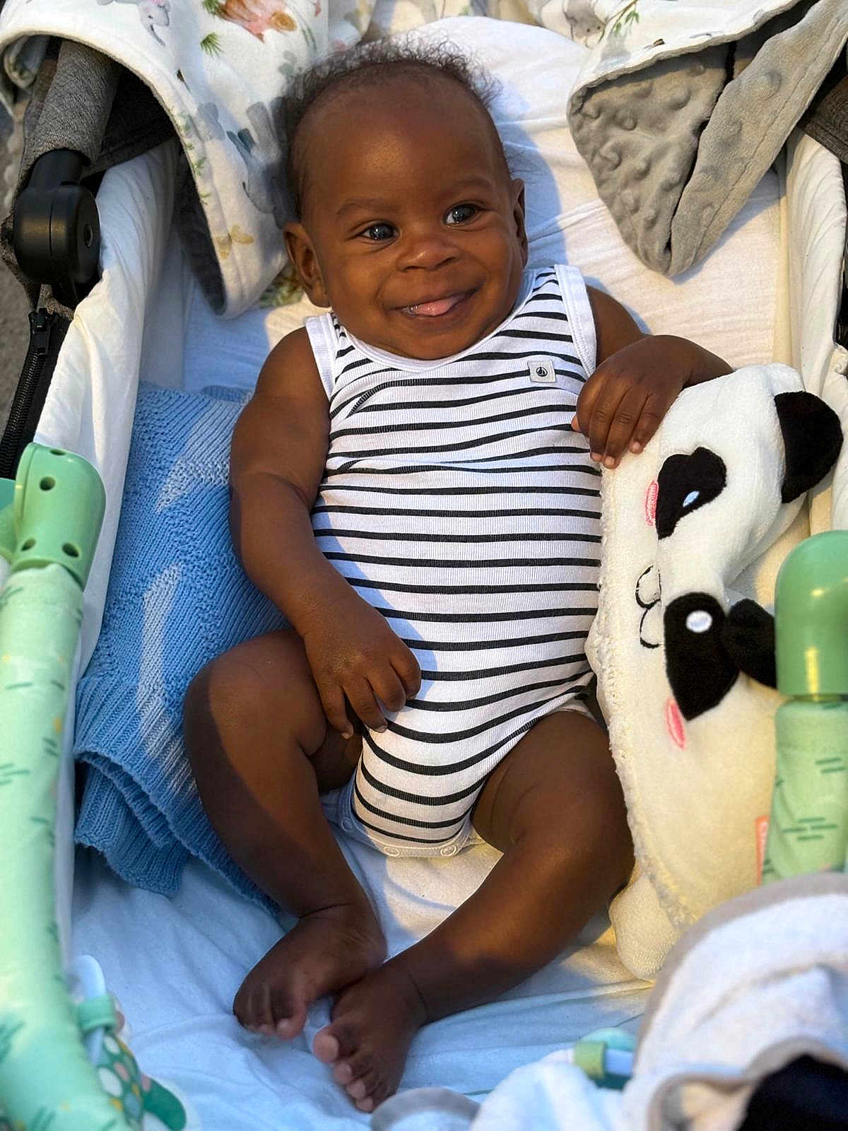 Leeroy a rejoint le concours — aidez-le/la à gagner de superbes lots ! baby, infant, smiling, striped_onesie, panda_plushie, blanket, stroller, cozy, happy, cute, child, soft_toy, comfort, indoors, portrait, relaxed, skin, feet, hand, face