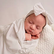 Ava is registered to the contest to win money with this photo: baby, newborn, sleeping, blanket, white, bow, headband, soft, cozy, wrapped, infant, peaceful, cute, portrait, child, indoors, texture, warm, resting, toddler
