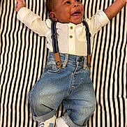 Neo joined the competition — help win amazing prizes! baby, infant, smiling, striped_blanket, white_shirt, suspenders, denim_jeans, sneakers, happy, lying_down, cute, child, portrait, casual_clothing, indoor, fashion, young_child, person, feet, hands