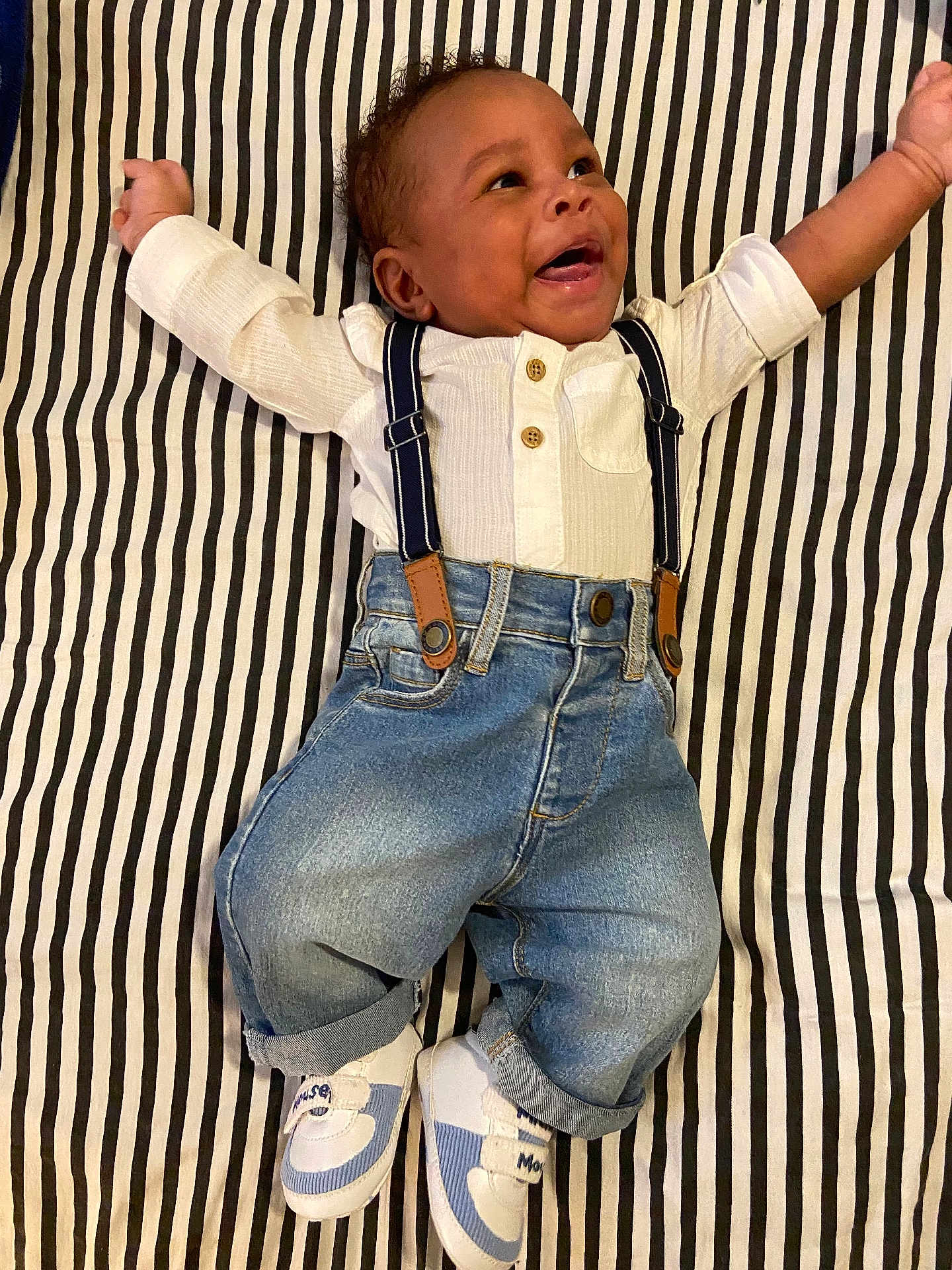Neo joined the competition — help win amazing prizes! baby, infant, smiling, striped_blanket, white_shirt, suspenders, denim_jeans, sneakers, happy, lying_down, cute, child, portrait, casual_clothing, indoor, fashion, young_child, person, feet, hands