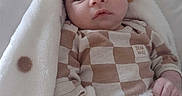 Kyren joined the competition — help win amazing prizes! baby, blanket, infant, face, person, clothing, checkered_pattern, cute, cozy, soft, indoors, portrait, newborn, hand, expression, sleepwear, comfortable, young_child, warm, resting