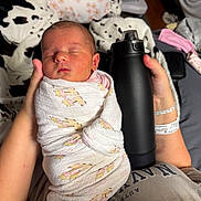 Ilaria is registered to the contest to win money with this photo: arm, baby, bed, blanket, comfort, cozy, fabric, giraffe_pattern, hand, hospital_bracelet, indoor, infant, newborn, person, pillow, resting, sleeping, soft_lighting, swaddled, water_bottle