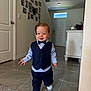 bow_tie, boy, carpet, child, door, face, floor, hair, hallway, indoor, pants, photographs, shirt, shoes, smiling, suit, toddler, walking, wall, white_sneakers