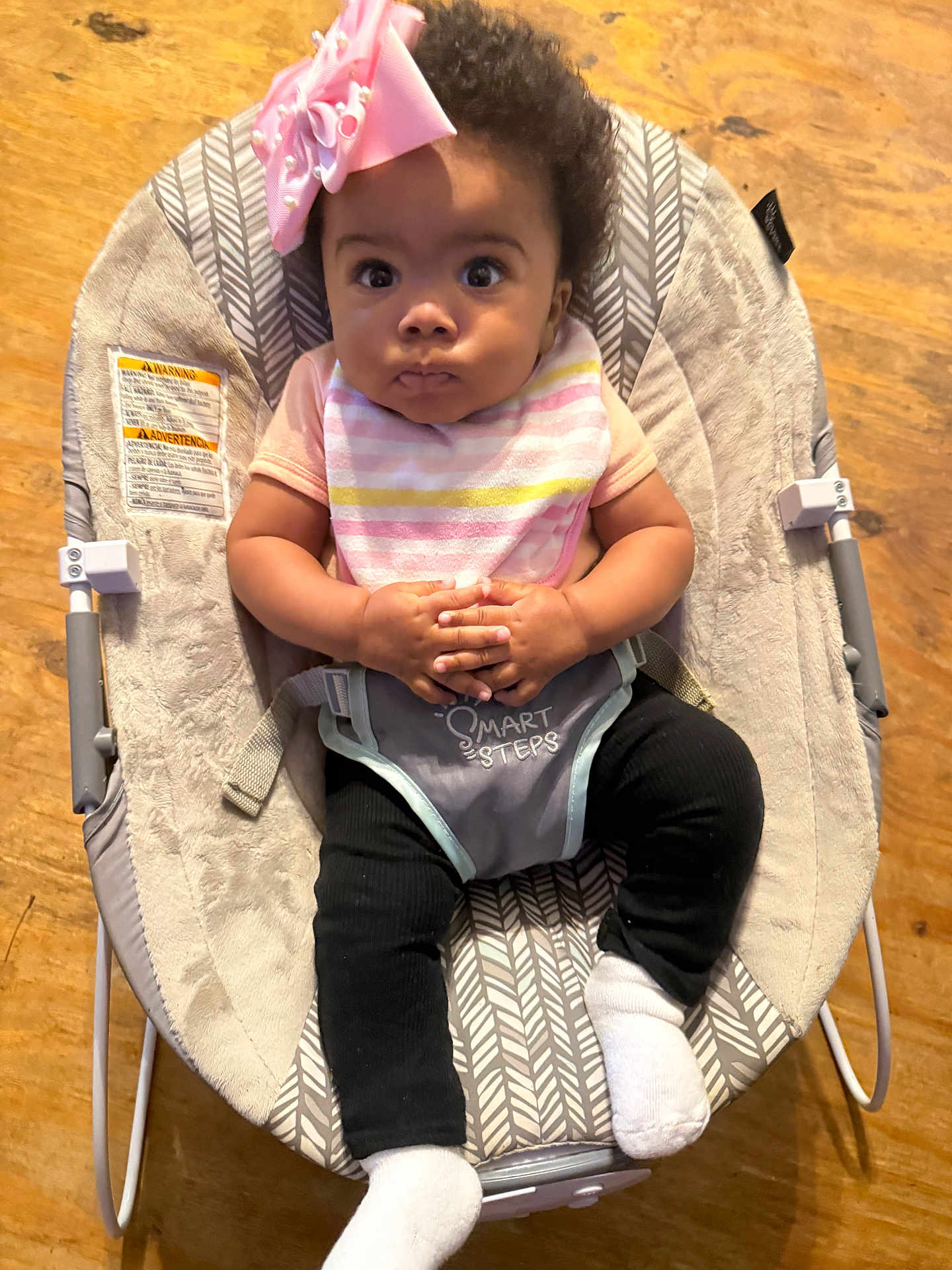 Icelynn joined the competition — help win amazing prizes! baby, infant, child, baby_rocker, pink_bow, bib, black_pants, white_socks, hands_clasped, wide_eyes, serious_expression, indoor, wooden_floor, baby_clothing, seat, comfort, portrait, cute, small_hands, young_child