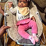 Icelynn is registered to the contest to win money with this photo: baby, infant, pink_bow, pink_pants, unicorn_socks, baby_rocker, bib, hand, floor, adult, indoor, cute, child, person, footwear, clothing, face, expression, seated, relaxed