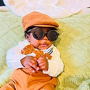 Stetson joined the competition — help win amazing prizes! baby, child, sunglasses, hat, bow_tie, suspenders, clothing, green_blanket, infant, cute, portrait, fashion, accessory, indoor, soft_texture, hands, face, smile, relaxed, person