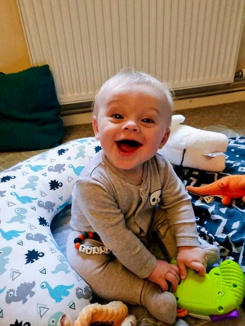 Tyler joined the competition — help win amazing prizes! baby, baby_playing_with_toys, baby_toddler_clothing, cheek, child, comfort, face, facial_expression, flooring, fun, green, happy, head, person, product, sitting, skin, smile, toddler, toy