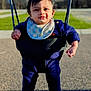 Rishi joined the competition — help win amazing prizes! baby, child, swing, playground, outdoor, smiling, happy, blue_clothing, bib, sunlight, shadow, grass, trees, winter, feet, sock, face, person, park, play