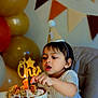 Rishi is registered to the contest to win money with this photo: toddler, birthday, cake, candle, party_hat, balloons, celebration, child, table, cream, cookie, decorations, indoor, happy, curious, person, food, festive, one_year, bunting