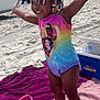 Chloe is registered to the contest to win money with this photo: child, toddler, beach, sand, swimsuit, colorful_beads, smiling, happy, pink_bucket, cooler, towel, outdoor, sunny, building, vehicle, vacation, summer, barefoot, playful, portrait
