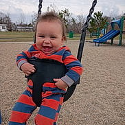 Zachary is registered to the contest to win money with this photo: baby, child, swing, playground, smiling, happy, outdoor, park, clothing, striped, seat, grass, bench, slide, person, fun, daytime, nature, tree, joy