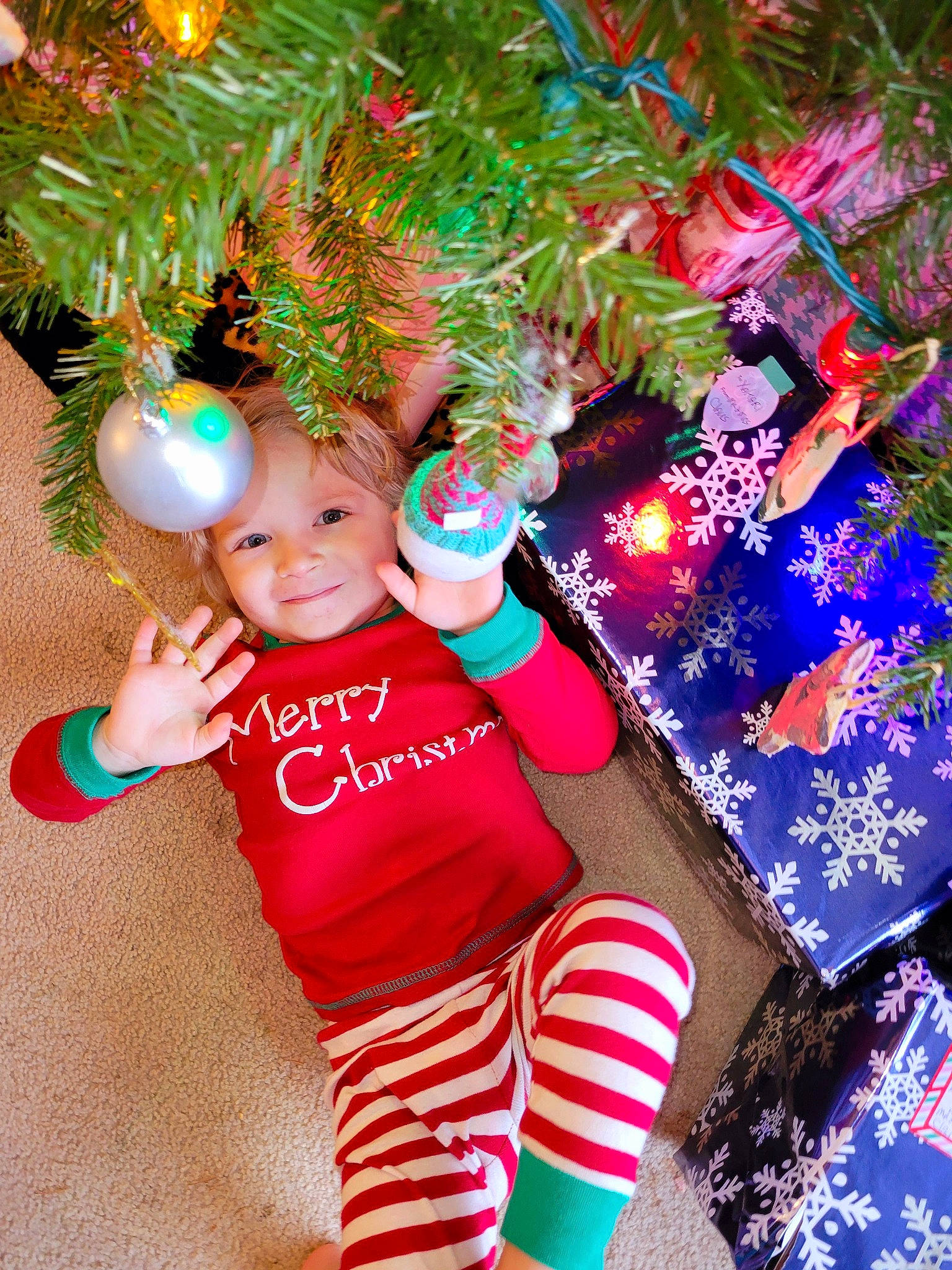Leo is registered to the contest to win money with this photo: baby_toddler_clothing, christmas, christmas_decoration, christmas_eve, christmas_ornament, christmas_tree, event, evergreen, fun, happy, headwear, holiday, holiday_ornament, joy, light, ornament, person, plant, sleeve, smile