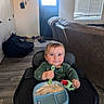 Jason joined the competition — help win amazing prizes! baby, blue_eyes, child, cute, door, feeding, flooring, food, green_clothing, high_chair, home, indoor, living_room, messy_face, person, smiling, sofa, spoon, teether, window