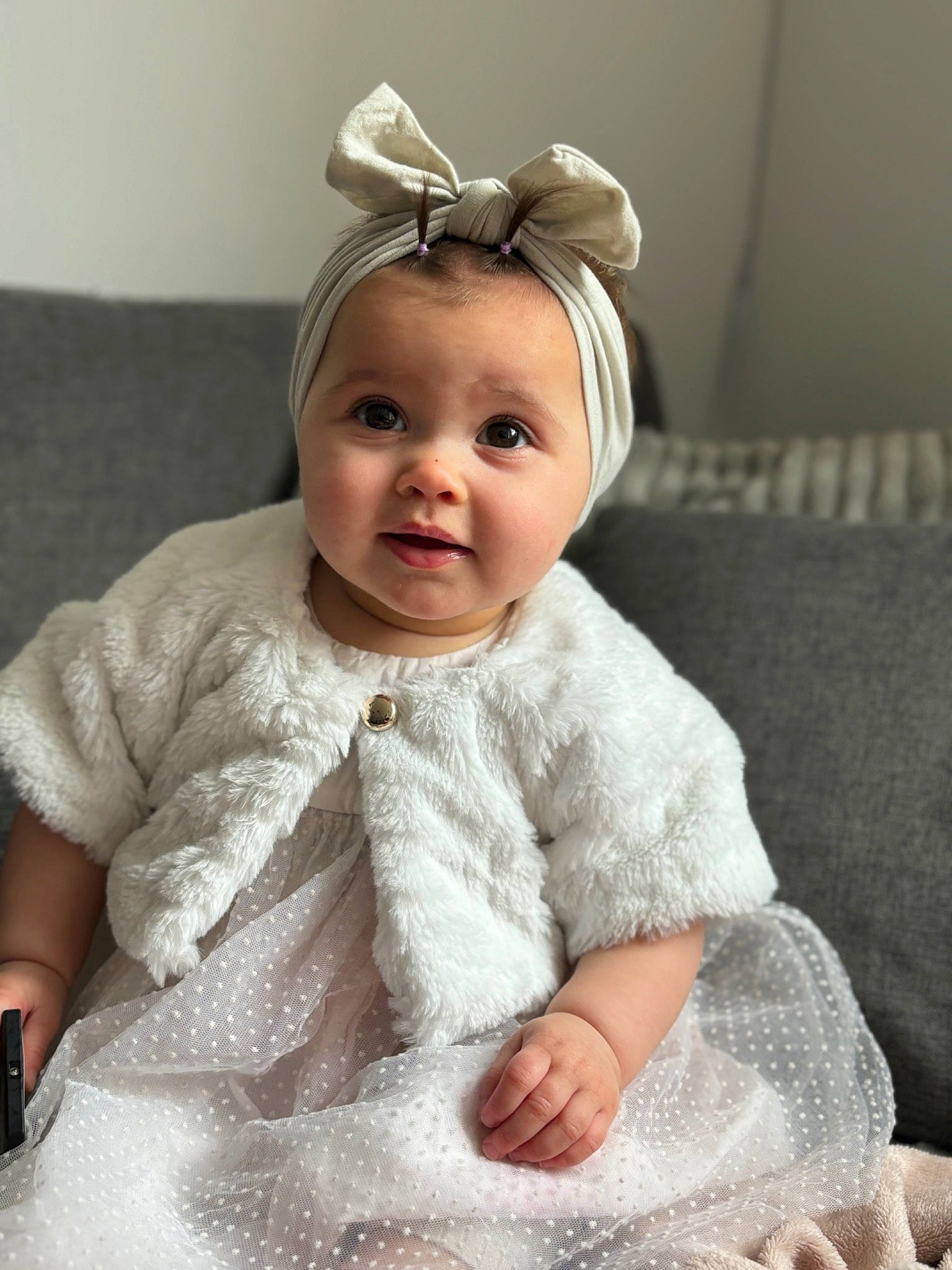 Elya participe au concours pour gagner de l'argent avec cette photo : baby, baby_toddler_clothing, child, comfort, dress, ear, embellishment, eye, eyelash, face, happy, headband, headpiece, iris, linens, lip, person, skin, sleeve, smile
