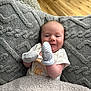 baby, blanket, mittens, couch, floor, wood_floor, smile, infant, face, clothing, texture, cozy, indoor, person, happy, head, seated, home, soft, young_child