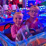Alba participe au concours pour gagner de l'argent avec cette photo : amusement_park, casual_clothing, child, children, colorful, entertainment, face, fun, glasses, happy, indoor, neon_lights, person, playful, portrait, ride, smile, toy_car, two_people, young