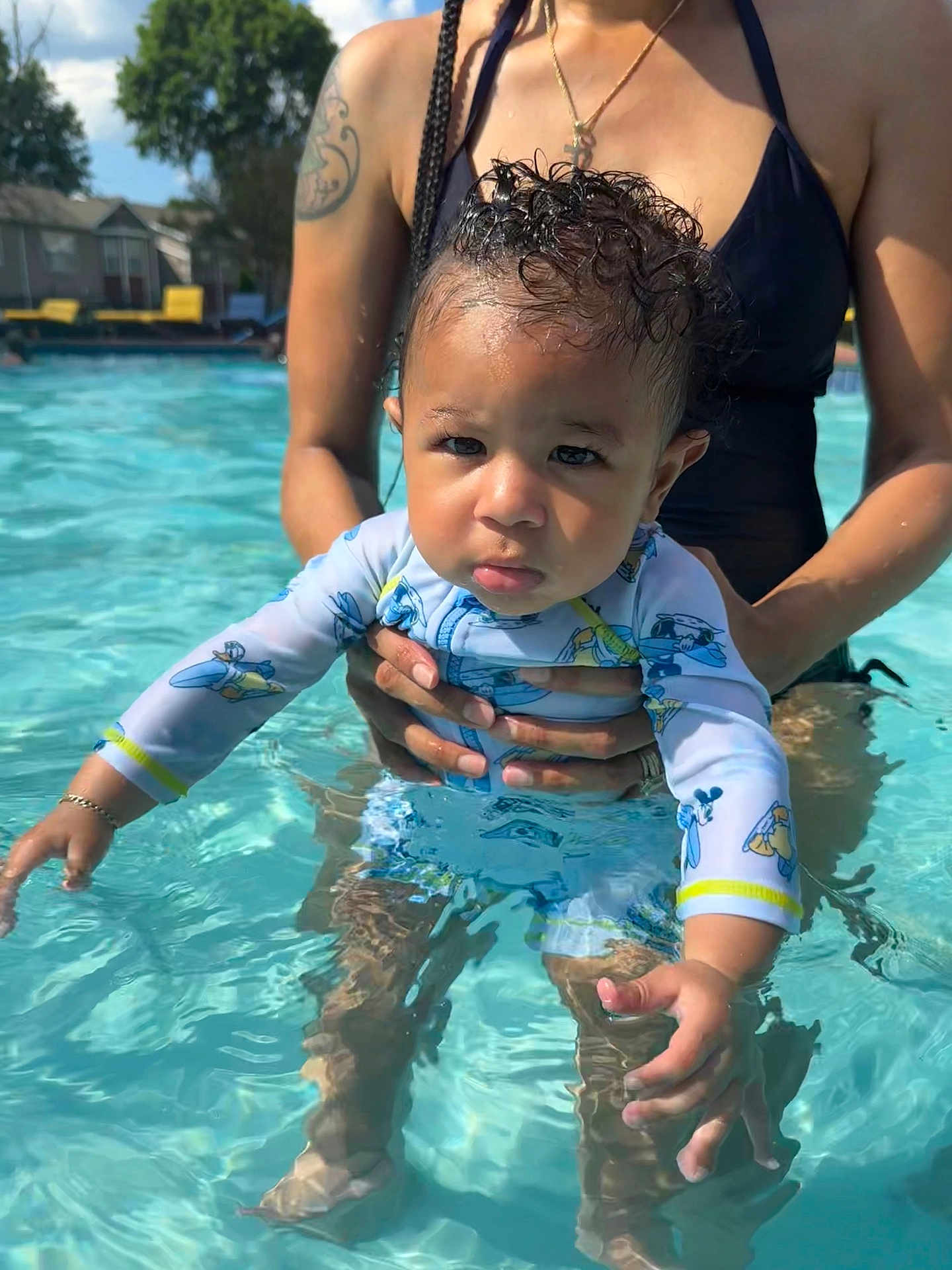 Khari is registered to the contest to win money with this photo: toddler, child, baby, pool, water, swimwear, adult, tattoo, sunlight, outdoor, summer, holding, cute, serious_face, swimming, parent, family, skin, daytime, recreation