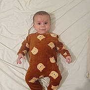 Eiden a rejoint le concours — aidez-le/la à gagner de superbes lots ! baby, infant, onesie, brown_clothing, bear_pattern, lying_down, white_sheet, cute, child, portrait, indoors, sleepwear, footed_pajamas, smiling, face, person, young_child, cozy, comfortable, sleeping_area