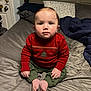 Mylo is registered to the contest to win money with this photo: toddler, child, baby, sitting, bed, sweater, red_sweater, green_pants, indoor, portrait, face, cute, looking_at_camera, cross_legged, pillow, blanket, home, young_child, casual, cozy