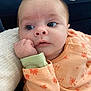 Lucie a rejoint le concours — aidez-le/la à gagner de superbes lots ! baby, blanket, blue_background, casual, closeup, curious, cute, expression, face, hand, indoors, infant, orange_clothing, patterned_clothing, person, portrait, resting, skin, soft_texture, young_child