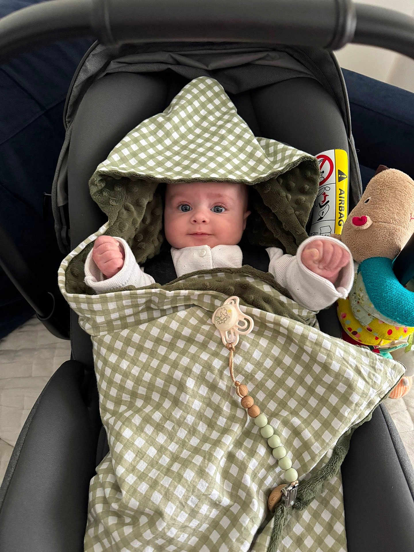 Lucie participe au concours pour gagner de l'argent avec cette photo : baby, blanket, car_seat, checkered_pattern, child, clothing, cute, face, fist, green, hood, indoor, infant, plush_toy, portrait, seat, smiling, toy, white_clothing, young_child