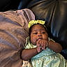 Legacy joined the competition — help win amazing prizes! baby, bow, child, cushion, dark_skin, dress, face, floral_pattern, green_clothing, hands, headband, home, indoor, infant, leather_couch, lying_down, photography, portrait, sitting, smiling