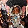 baby, black, car_seat, child, curious, fabric, face, feet, floral_outfit, flower, hands, headband, indoor, infant, photography, pink, portrait, safety_straps, sitting, white_socks