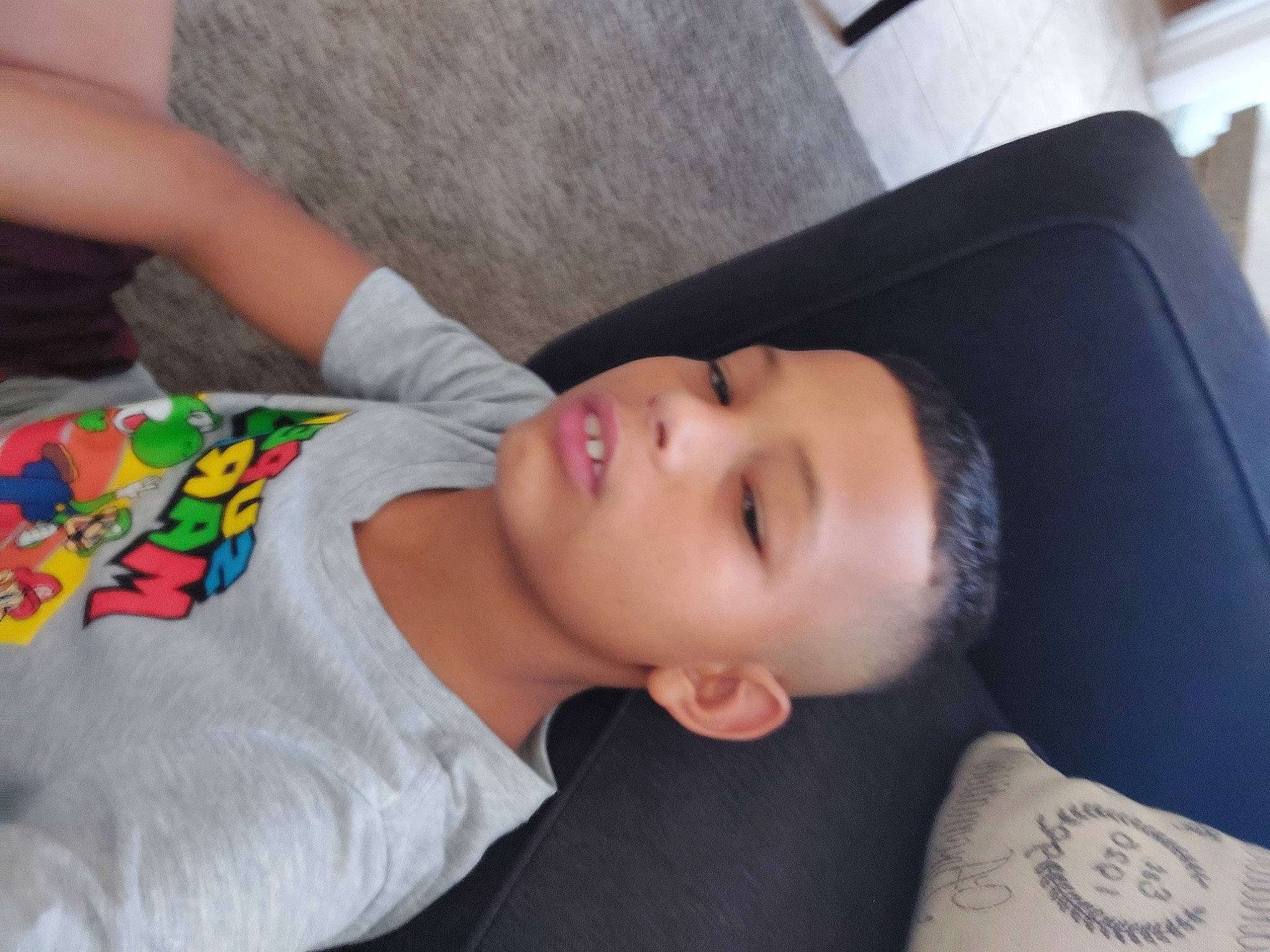 Larry is registered to the contest to win money with this photo: black_hair, car_seat, cheek, child, comfort, couch, elbow, eyebrow, eyelash, linens, nail, nap, neck, nose, pattern, person, room, sleep, sleeve, t_shirt