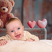 Louise participe au concours pour gagner de l'argent avec cette photo : baby, smiling, blanket, teddy_bear, heart_shape, plush, cute, child, infant, happy, soft, cozy, portrait, indoor, warm_lighting, candid, love, cute_face, furniture, decor