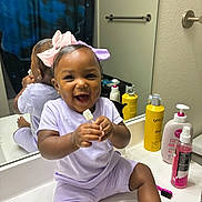 Nahairelanae joined the competition — help win amazing prizes! toddler, child, smiling, bathroom, mirror, sink, bow, purple_clothing, pink_bow, reflection, toiletries, lotion_bottle, spray_bottle, shower_curtain, happy, sitting, holding_object, cute, indoor, person