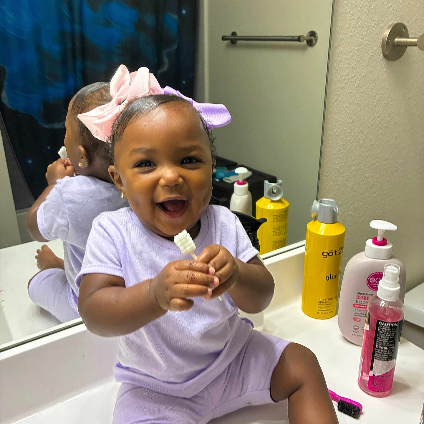 Nahairelanae joined the competition — help win amazing prizes! toddler, child, smiling, bathroom, mirror, sink, bow, purple_clothing, pink_bow, reflection, toiletries, lotion_bottle, spray_bottle, shower_curtain, happy, sitting, holding_object, cute, indoor, person