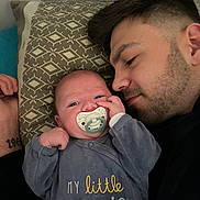 Léandre participe au concours pour gagner de l'argent avec cette photo : affection, baby, bed, closeup, clothing, face, facial_hair, family, hand, head, indoor, man, pacifier, patterned_pillow, pillow, portrait, resting, sleeping, tattoo, toddler