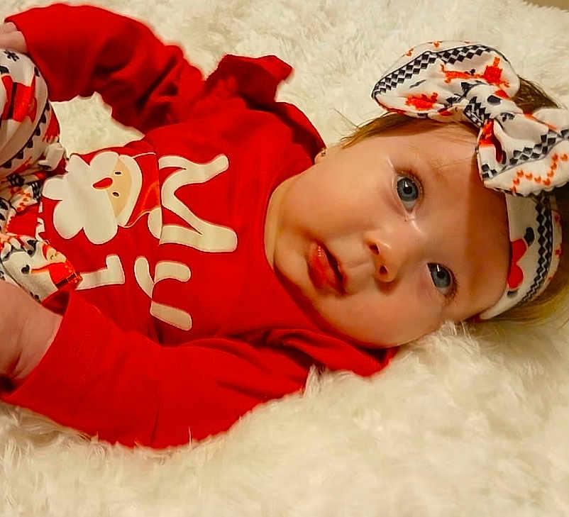 Azaria joined the competition — help win amazing prizes! baby, infant, red_clothing, headband, bow, blue_eyes, lying_down, fluffy_surface, cute, child, festive, holiday_outfit, portrait, person, soft_texture, indoor, face, expression, newborn, adorable